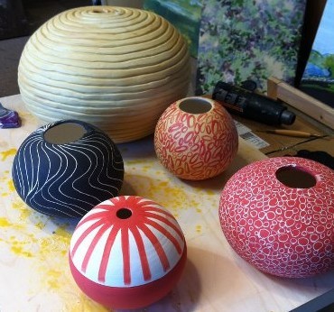 Large ceramic "beads" after firing in the kiln, before becoming sculptures (see finished piece at right made from red sphere above)